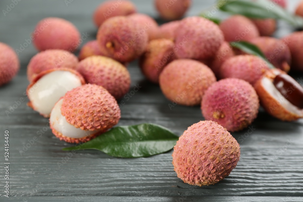 Fresh ripe lychee fruits on grey wooden table, closeup Fresh ripe lychee fruits on grey wooden table, closeup