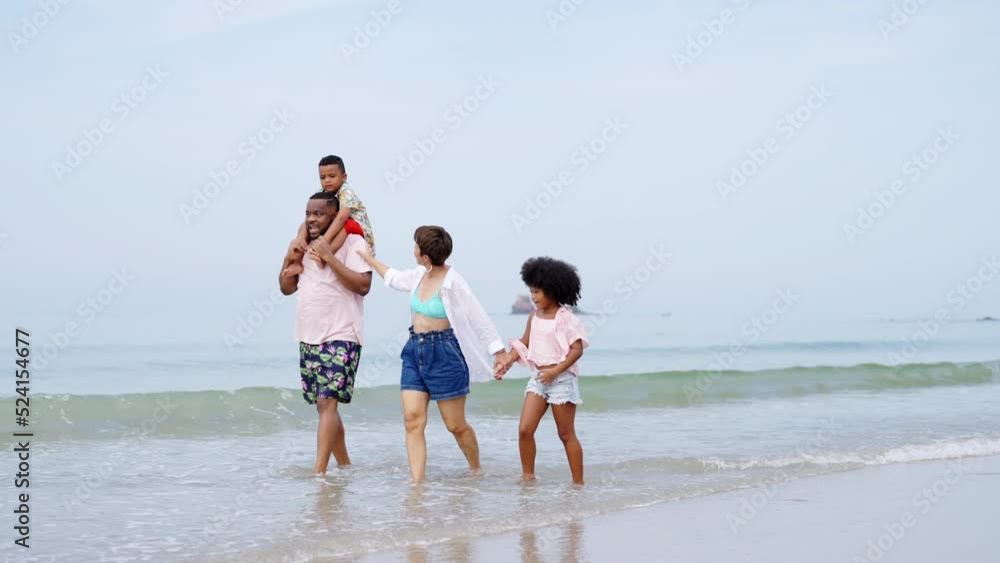 4K African family on beach holiday vacation. Father and mother with little daughter and son playing together on the beach at summer sunset. Parents with kid enjoy outdoor lifestyle together at the sea 4K African family on beach holiday vacation. Father and mother with little daughter and son playing together on the beach at summer sunset. Parents with kid enjoy outdoor lifestyle together at the sea