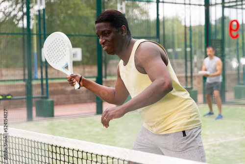 Portrait of focused man paddle tennis player during doubles couple match at court © JackF