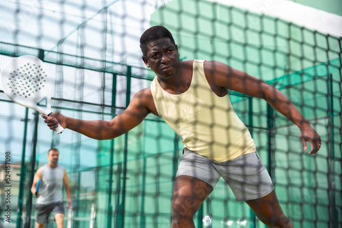 View through the tennis net of an african american playing padel. High quality photo