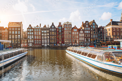 Amsterdam canal cruise ship with Netherlands traditional house in Amsterdam  Netherlands.