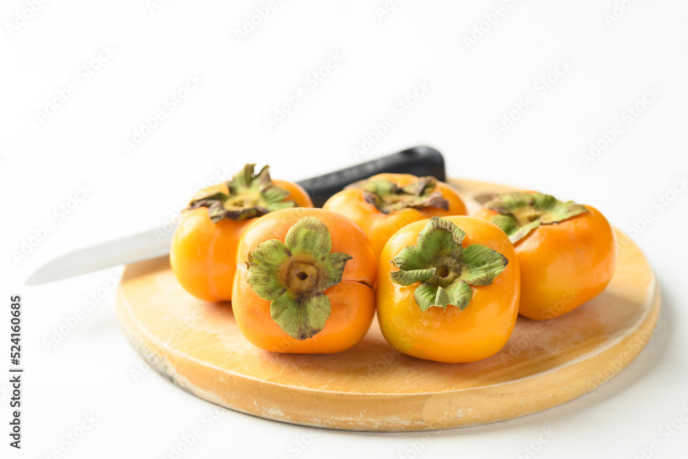 Ripe persimmon fruit on cutting wooden board with knife prepare for cooking Ripe persimmon fruit on cutting wooden board with knife prepare for cooking