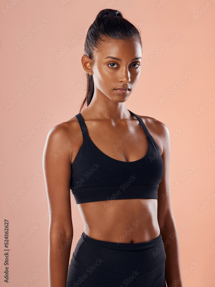 Fit, slim and serious woman feeling confident about her body and health while standing against a pink studio background. Portrait of a sporty and determined woman ready to exercise to stay in shape Fit, slim and serious woman feeling confident about her body and health while standing against a pink studio background. Portrait of a sporty and determined woman ready to exercise to stay in shape