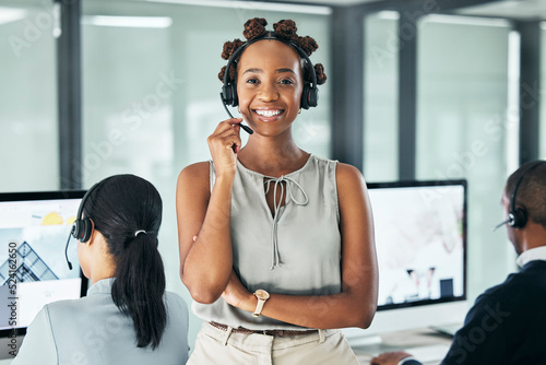 Call center agent leader standing with arms crossed, looking proud and wearing a headset in an office with colleagues. Portrait of a smiling female customer service working looking confident photo