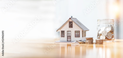 house model and money coins saving for concept saving money for buying a house, investment mortgage finance, and home loan refinance financial plan home loan. © David