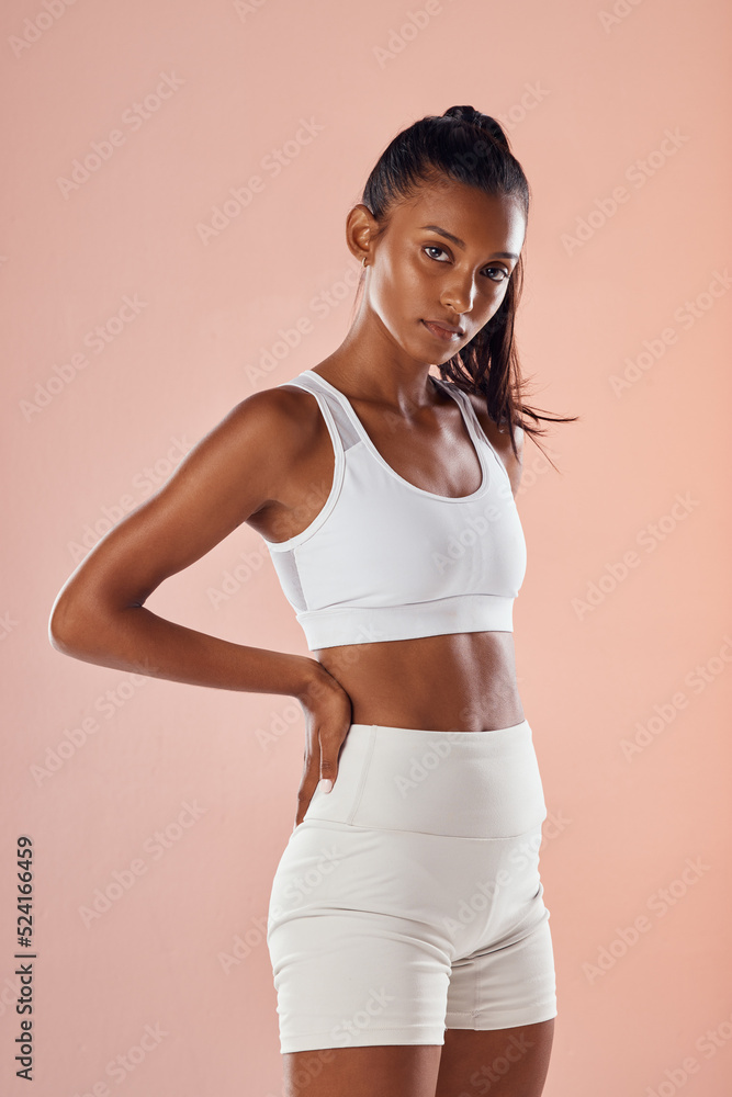 Wellness, health and fitness with a tough woman looking sporty and feeling confident against a pink background. Portrait of a motivated, slim, proud athlete satisfied with her physical and body goals