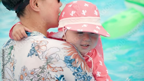 Korean mother embracing daughter in swimming pool - slow motion close-up photo