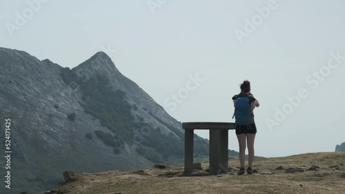 Fixed Shot Of Woman Standing In Front Of Stand In Virgin Nature, Looking Through Binocular, Anboto Vizcaya, Basque Country photo