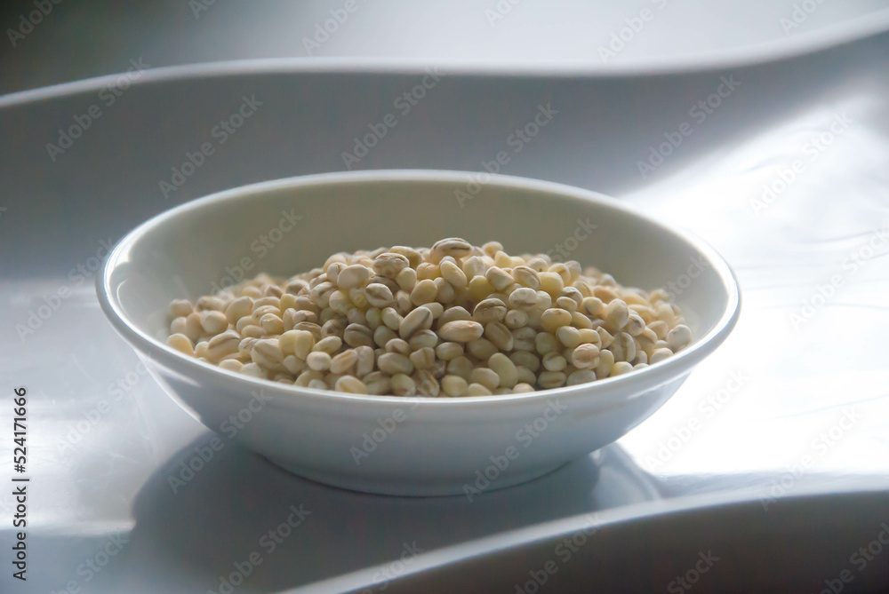 Bowl of organic pearl barley on white plate Bowl of organic pearl barley on white plate