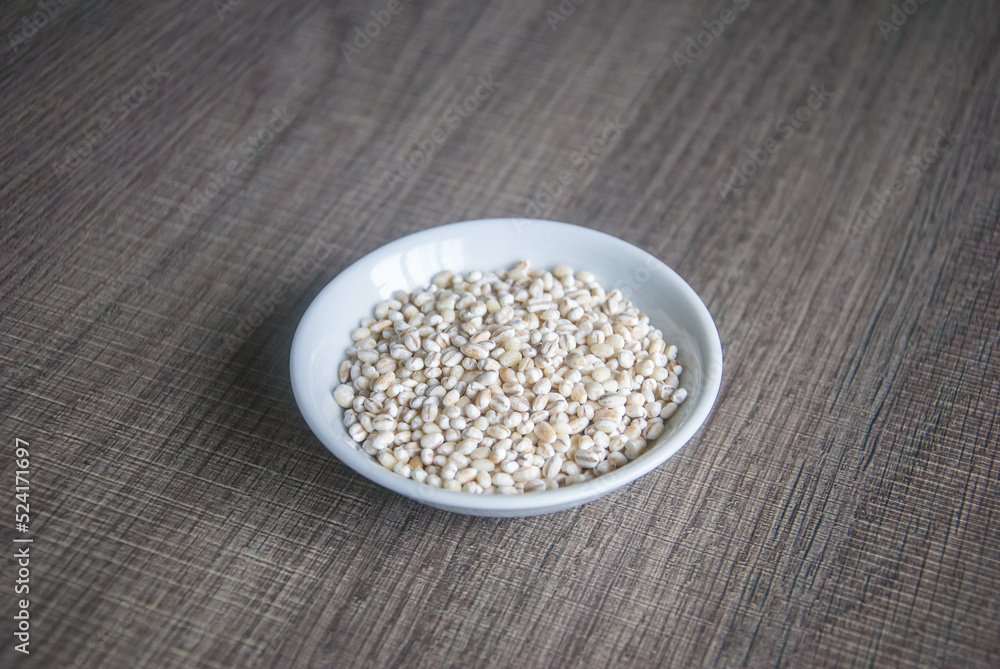 Bowl of organic pearl barley on white plate Bowl of organic pearl barley on white plate