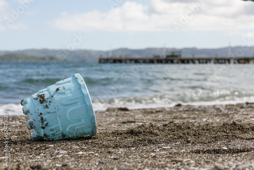 Blue plastic toy bucket partially buried in the sand
