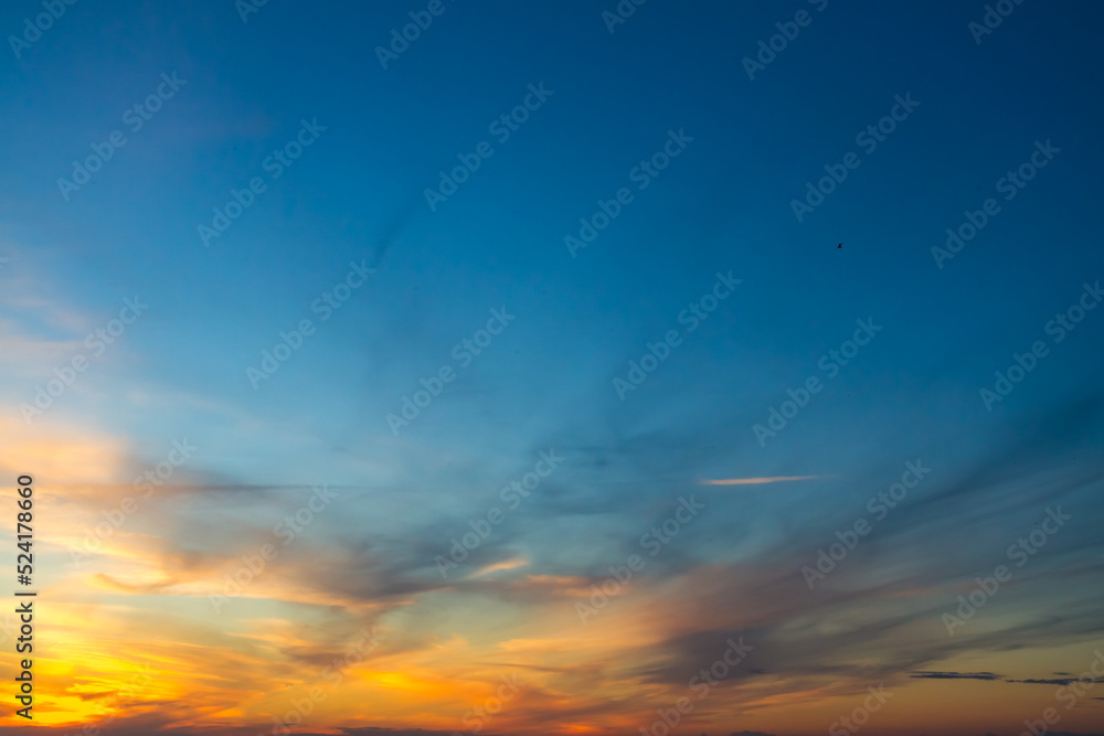 The sky at sunset or sunrise with orange clouds and a blue tint