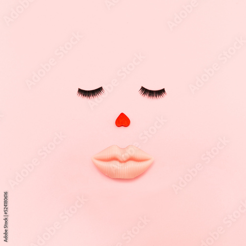 Outlines of an attractive female face with full lips  eyelashes and a heart-shaped nose on a pink pastel background. Concept art.