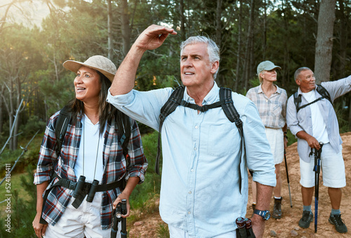 . Hiking, adventure and exploring with a group of senior friends having fun, exercising and enjoying the outdoors. Walking, discovery and journey with old people sightseeing in the forest or woods. photo