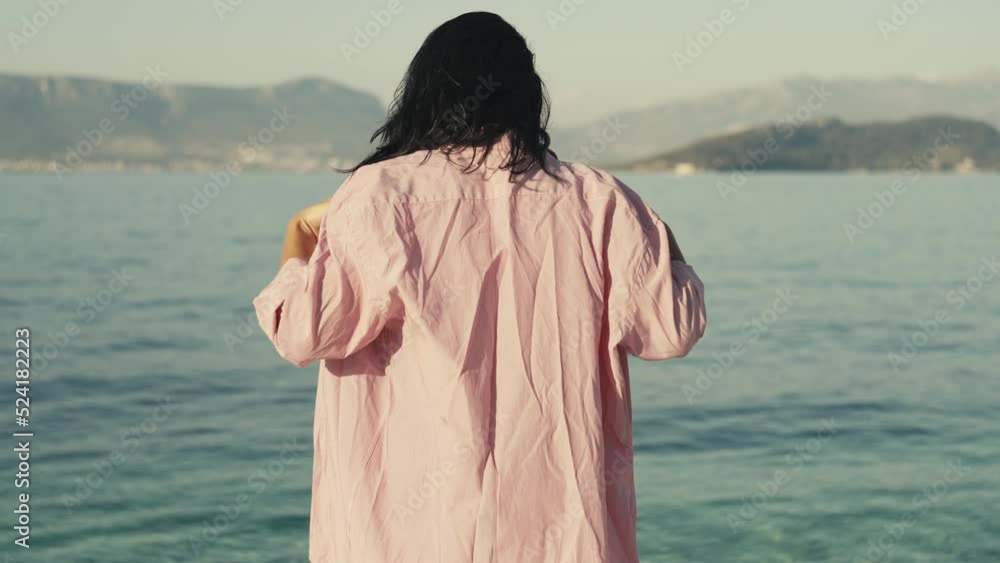 Slow motion video of a girl takes off her shirt on the beach and goes swimming. Woman on vacation in bikini goes swimming in the ocean. High quality 4k footage