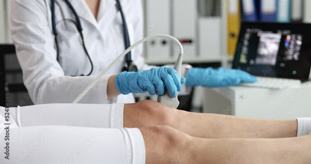 Doctor makes ultrasound of knee joint of woman using ultrasound scanner in clinic Doctor makes ultrasound of knee joint of woman using ultrasound scanner in clinic
