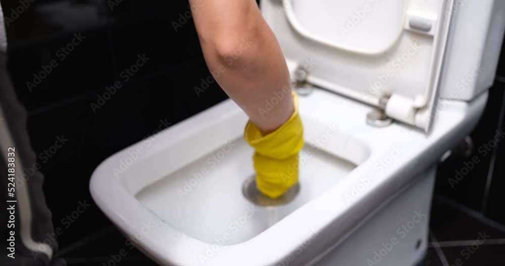 Housewife in yellow gloves washes white toilet bowl with brush at home Housewife in yellow gloves washes white toilet bowl with brush at home