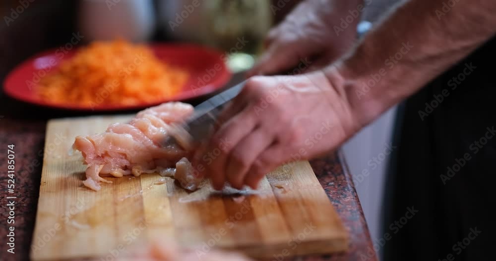 Male hands with knife cuts tender turkey fillet chicken or meat on wooden board Male hands with knife cuts tender turkey fillet chicken or meat on wooden board