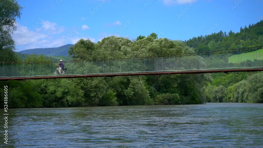 People cycling over bridge crossing river in beautiful Slovakia nature People cycling over bridge crossing river in beautiful Slovakia nature