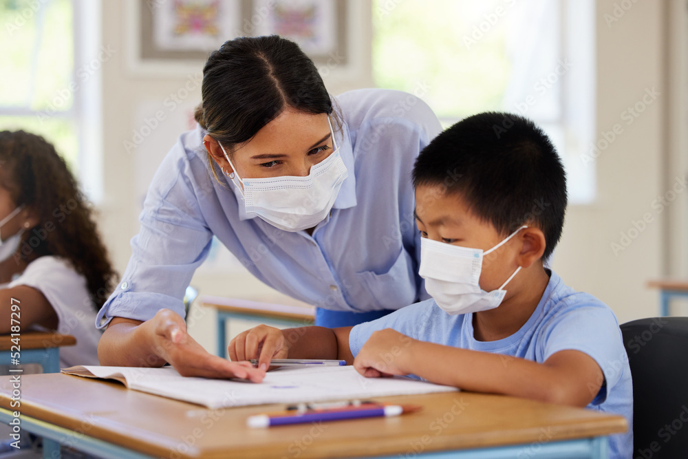 Covid, students and education teacher helping learning children in school classroom to answer math question. Woman with face mask teaching asian boy in lesson with diverse class of kids or classmates Covid, students and education teacher helping learning children in school classroom to answer math question. Woman with face mask teaching asian boy in lesson with diverse class of kids or classmates