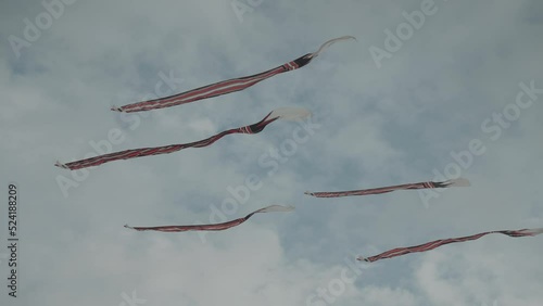 Balinese Traditional Kites JANGGAN (Red White Black Long Tail Bird Dragon) on Bali Kite Festival Summer Blue Sky Slow Motion photo