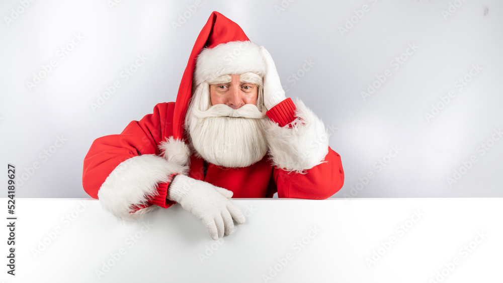 Santa Claus peeks out from behind an ad on a white background. Merry Christmas.