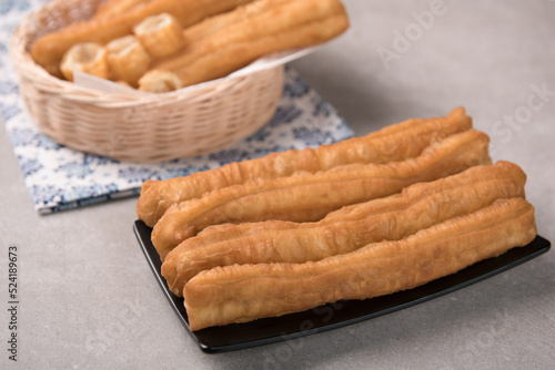 Cakwe or You tiao is a long golden-brown deep-fried strip of dough or typical chinese doughnut. Served in bamboo woven plate photo