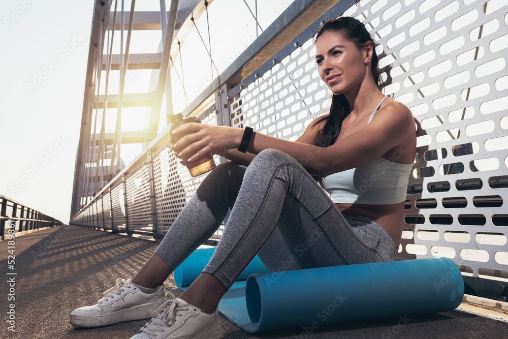 Fitness woman drinking water from bottle. Muscular young female taking a break from workout outside. Fitness woman drinking water from bottle. Muscular young female taking a break from workout outside.