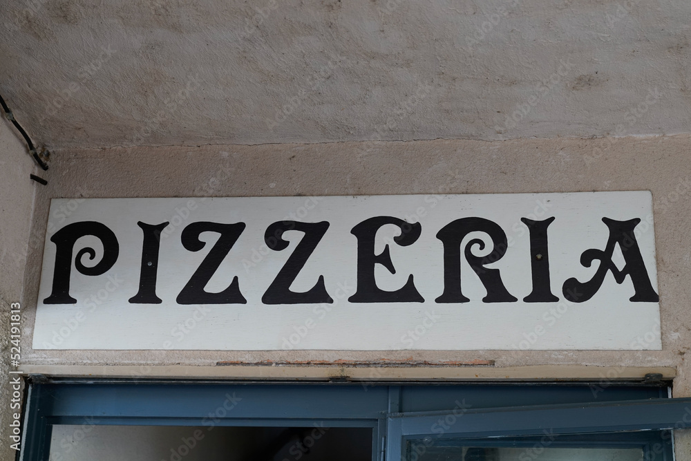 Obraz premium Pizzeria text sign from Italy on facade street outside entrance door restaurant italian