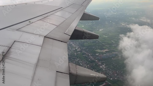 Aircraft window view wing flying from above air. Aerial view landscape airplane clouds.