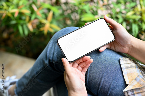 Top view, A female using her smartphone to watch an online video. phone white screen mockup. photo