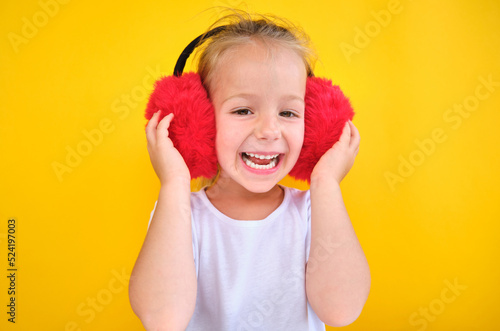 happy Cute little girl wearing stylish red earmuffs on yellow background photo