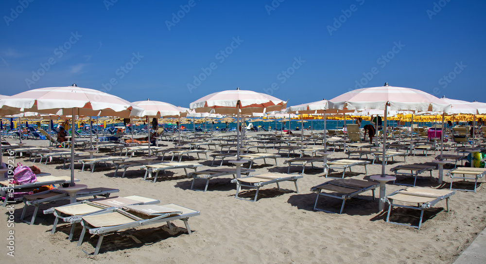 Italian beach view with umbrellas and sunbeds. Summer day on the beach. Riviera Romagnola, Italy
