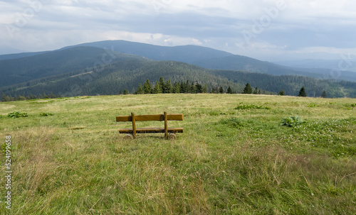 A bench in a meadow in front of the mountain shelter in Hala Rysianka in Beskid Zywiecki in Poland, where you can sit and admire the picturesque views of the surrounding areas