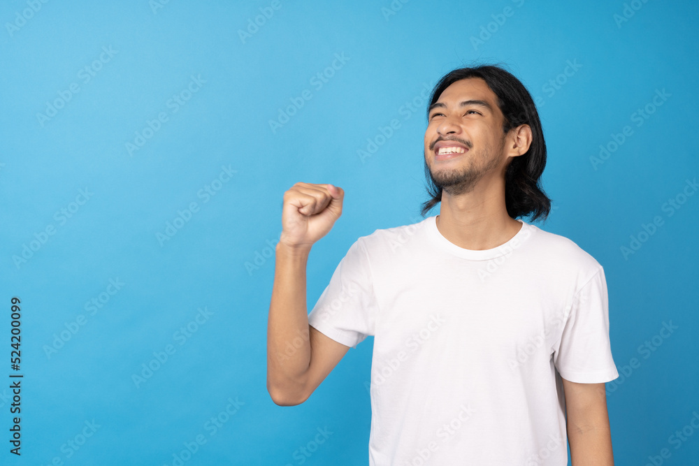 Cool asian man excited and surprised on blue background. A man saw a sale on an online shopping website or See the results of the football team cheering competition. Cool asian man excited and surprised on blue background. A man saw a sale on an online shopping website or See the results of the football team cheering competition.