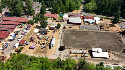 Wide aerial view of a rodeo arena, carnival rides, and barns at the Langley county fairgrounds. photo