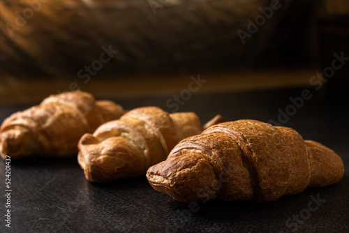 Close-up of golden croissants on a dark background. French pastries. Rustic breakfast.