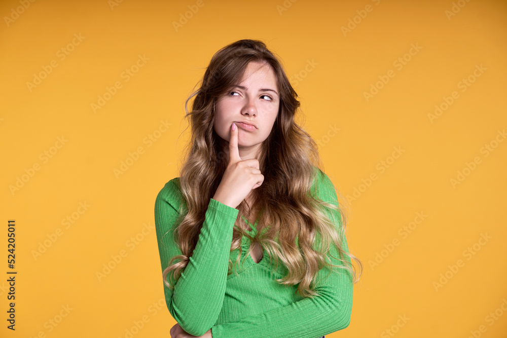 Thoughtful caucasian teenage girl on yellow background Thoughtful caucasian teenage girl on yellow background
