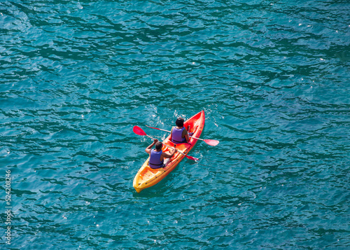 Happy couple in sea vests sailing a kayak