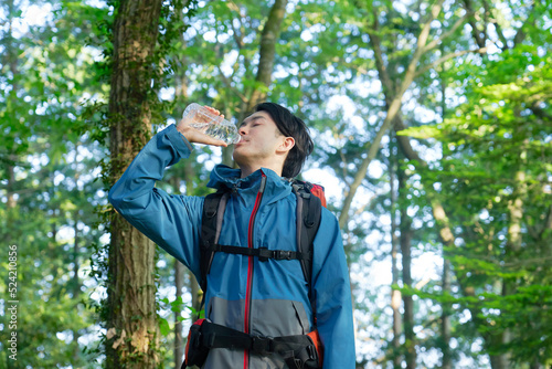 ペットボトルの水を飲んで水分補給する登山者
