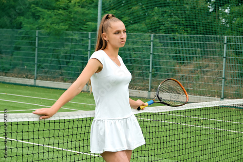 girl in a white sports dress on the tennis court. tennis court and racket. © Dmytrii