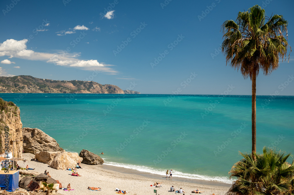 Travel destination, view on sandy beach, blue sea and mountains from Balcon de Europa in small Andalusian town Nerja with white houses and narrow streets on Costa del Sol, Spain