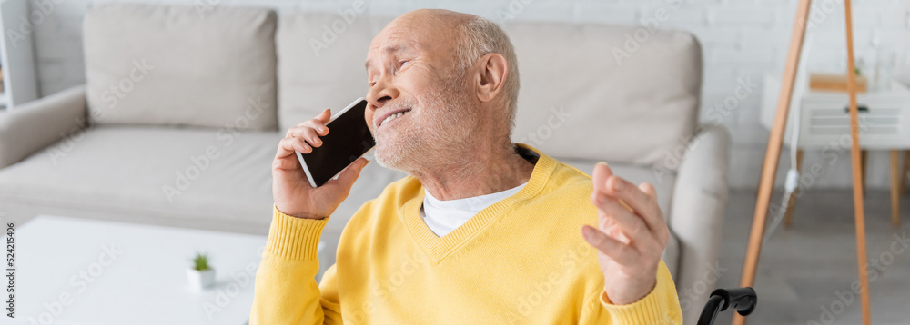 Cheerful elderly man talking on mobile phone at home, banner.