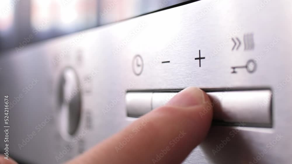 Turning on the mode switch and setting the time on electric oven. Male hand turns on the oven close-up. Setting modes for cooking food. Concept of housework, restaurant, cook turns on the stove Turning on the mode switch and setting the time on electric oven. Male hand turns on the oven close-up. Setting modes for cooking food. Concept of housework, restaurant, cook turns on the stove
