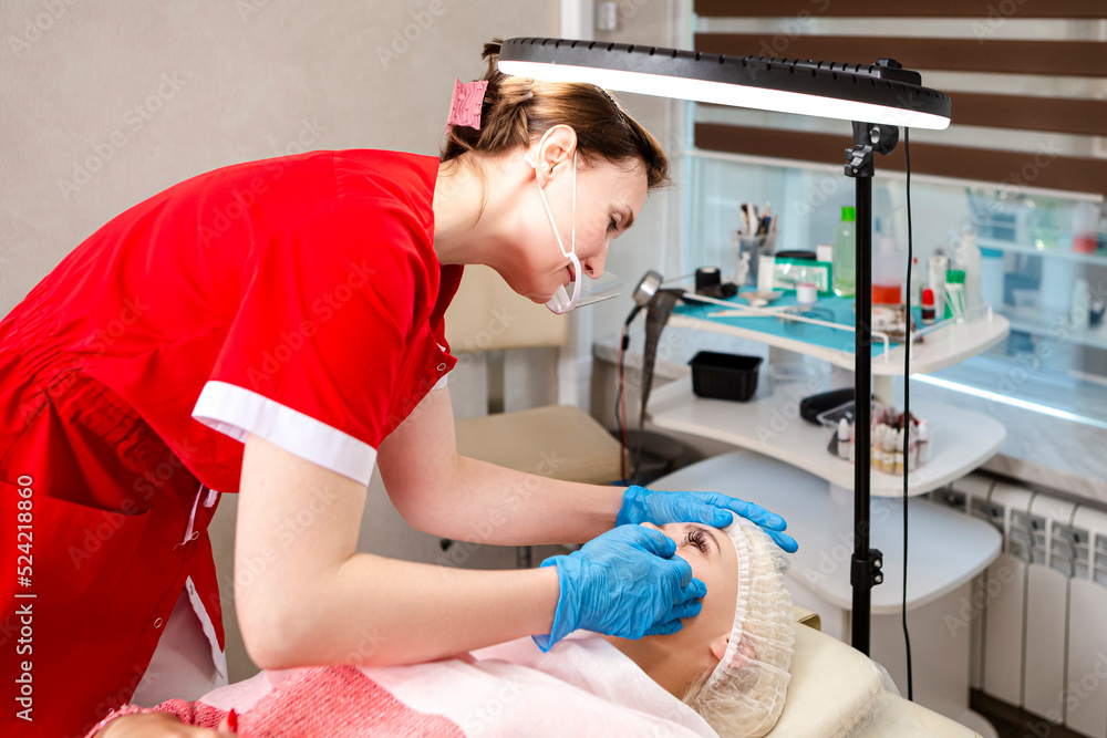 Microblading and Micropigmentation. Eyebrows Workflow in Beauty Salon While Caucasian Woman Having Eyebrows Drawn and Color Tinted With Semi-permanent Eyebrows Makeup.