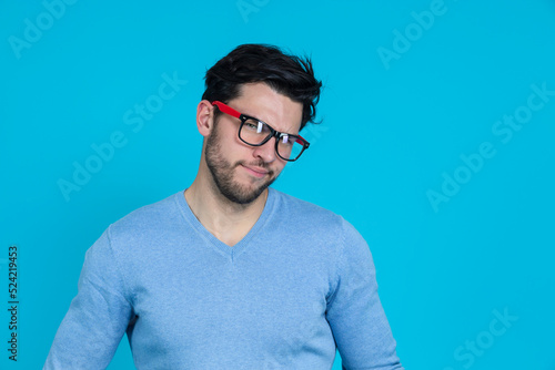 Extravagant Young Funny Handsome Caucasian Man in Glasses With Folded Hands Having Fun Against Seamless Blue Background © danmorgan12