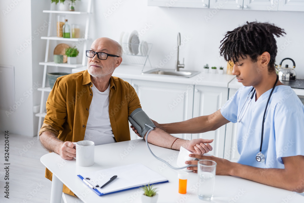 African american nurse checking blood pressure of elderly patient at home. African american nurse checking blood pressure of elderly patient at home.