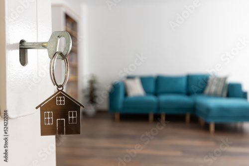 Open door to a new home. Door handle with key and home shaped keychain. Mortgage, investment, real estate, property and new home concept photo