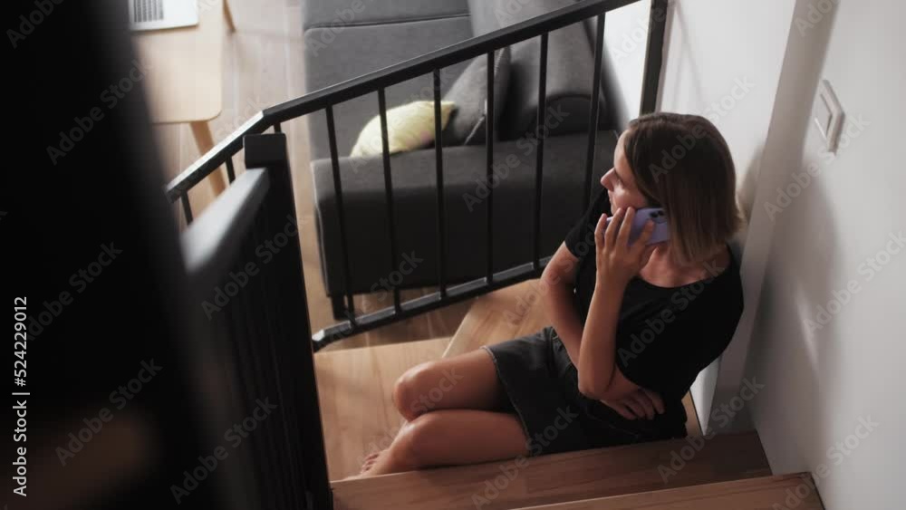 Smiling young woman talking on mobile phone at home, resting in living room alone.