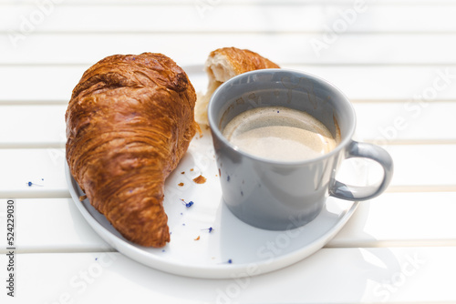 Crispy croissant and fresh coffee at the outdoor cafe. Breakfast, lunch concept.